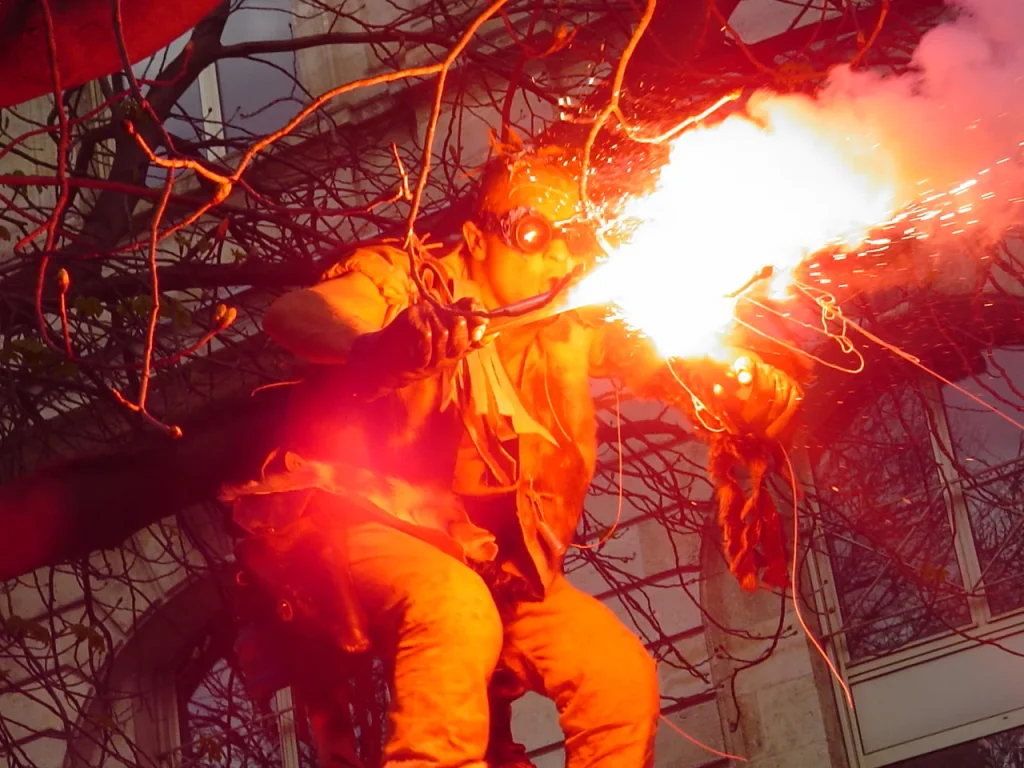 Un personnage en orange dans un arbre, une torche allumée à la main