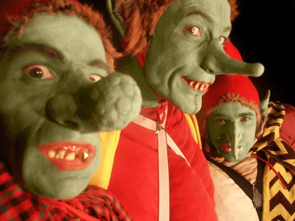 Trois personnages aux masques verts et aux bonnets rouges