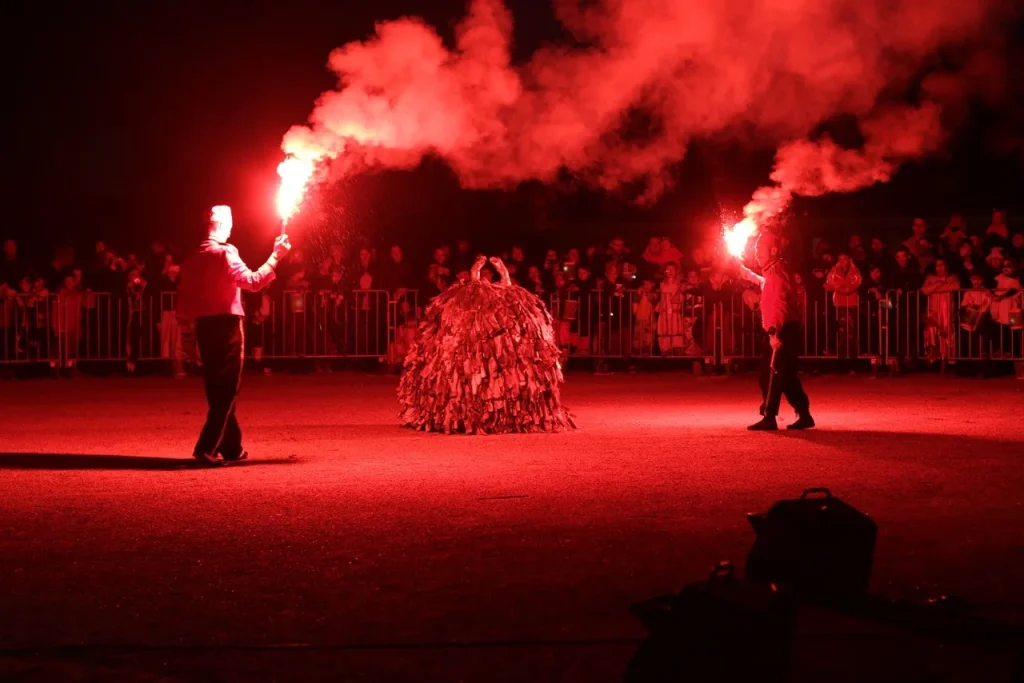 Deux artificiers brandissent des feux de Bengale rouges devant le public