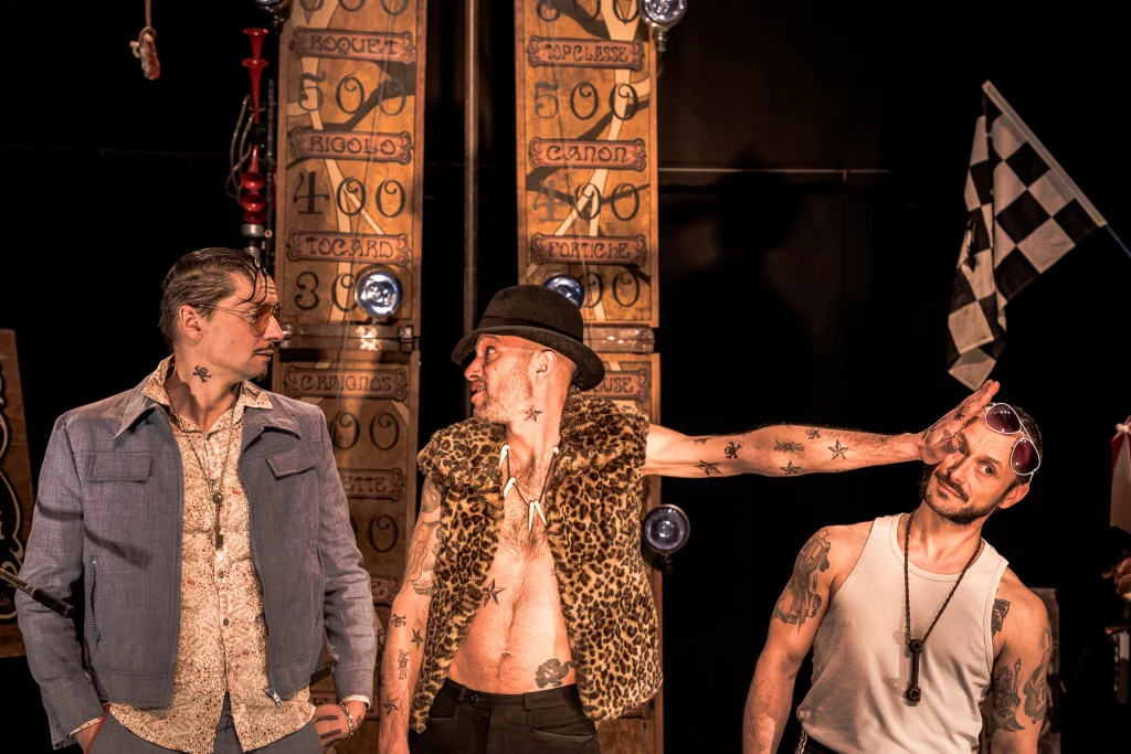 Trois Martoche tatoués devant le high striker, l’un en gilet léopard pose la main sur la tête d’un autre
