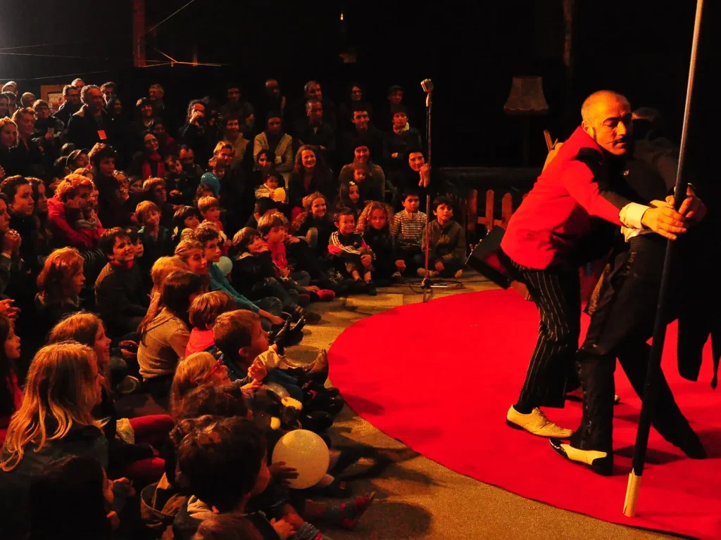 Un Groom en veste rouge sur un tapis rouge, devant des enfants assis par terre
